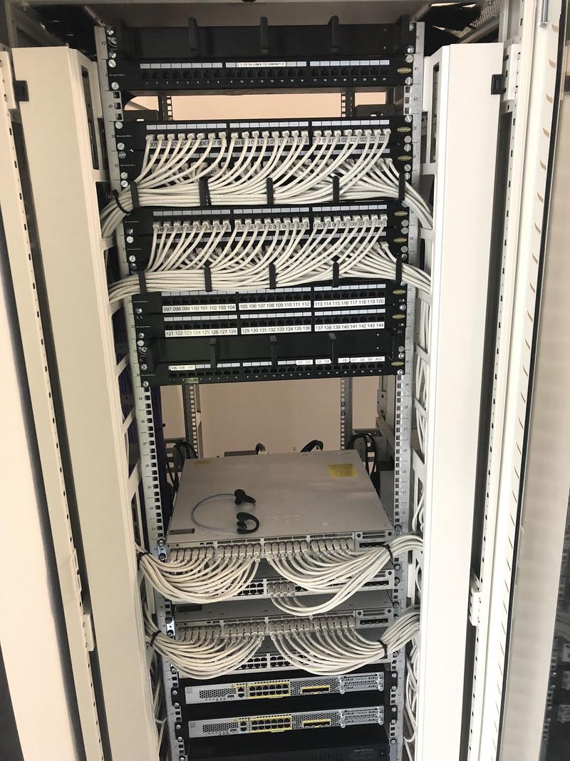 Comms cabinet with patch panels and white patch leads, installed by Elite Services