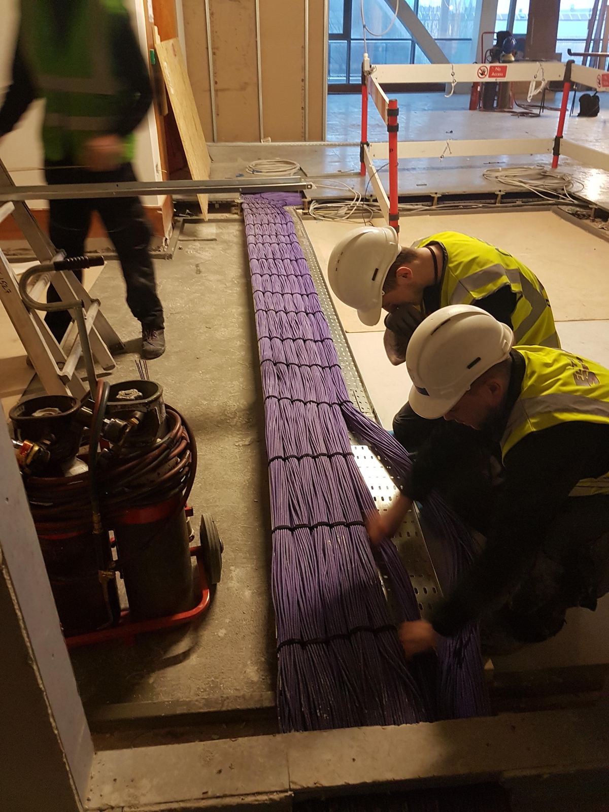 Elite Services engineers laying bundles of data cable on a fit-out site